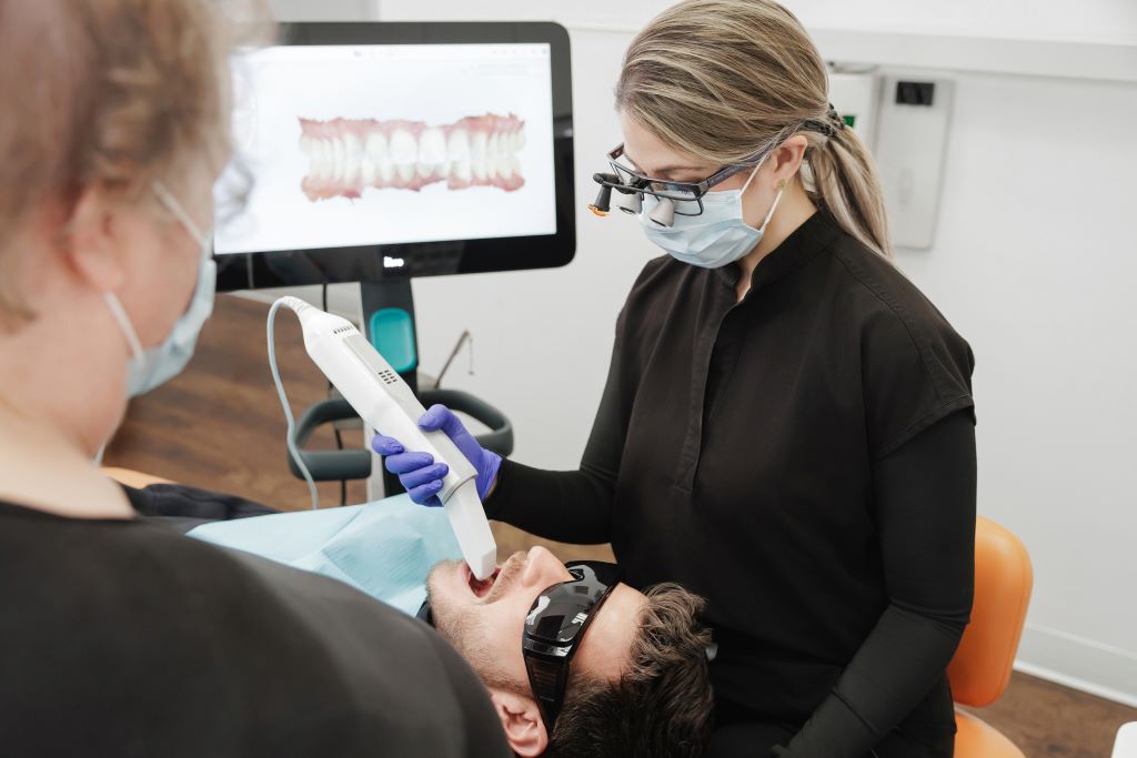 Calma Dental dentist member using a digital intraoral scanner to capture a patient's teeth on chairside monitor